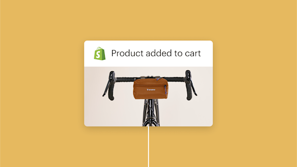 Brown handlebar bag mounted on black bicycle handlebars with Shopify logo and "Product added to cart" text above